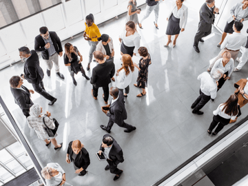 A group of people networking and conversing in a bright, modern event space, symbolizing collaboration and community engagement at a hemp industry gathering.